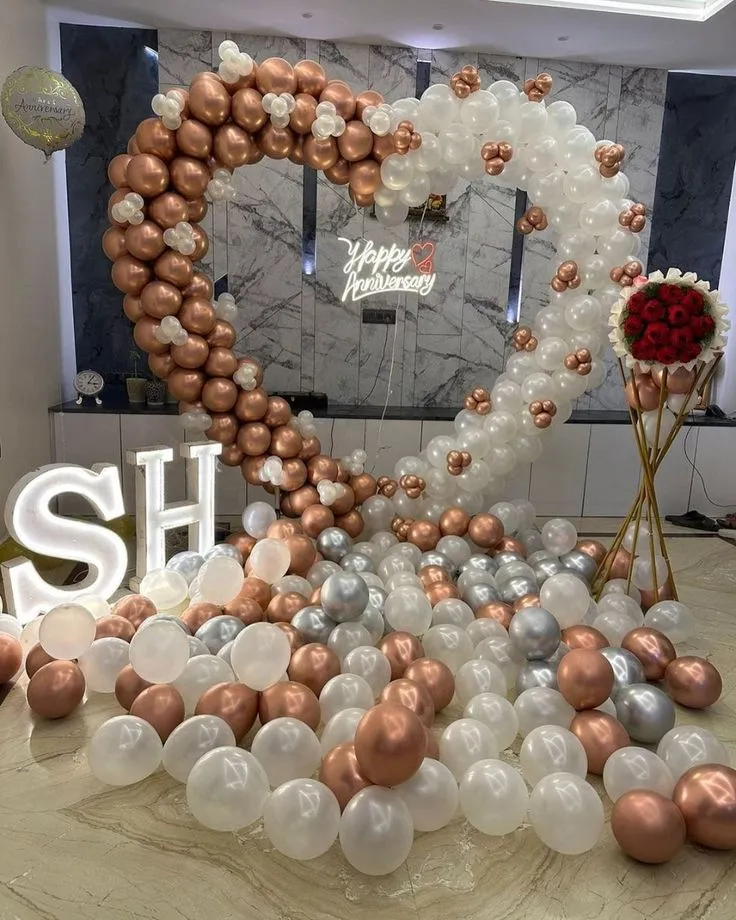 Anniversary balloon decoration with rose gold, white and silver balloons, neon light wall, anniversary foil balloon, and 15 roses bouquet in Dubai, UAE by Event Experts.
