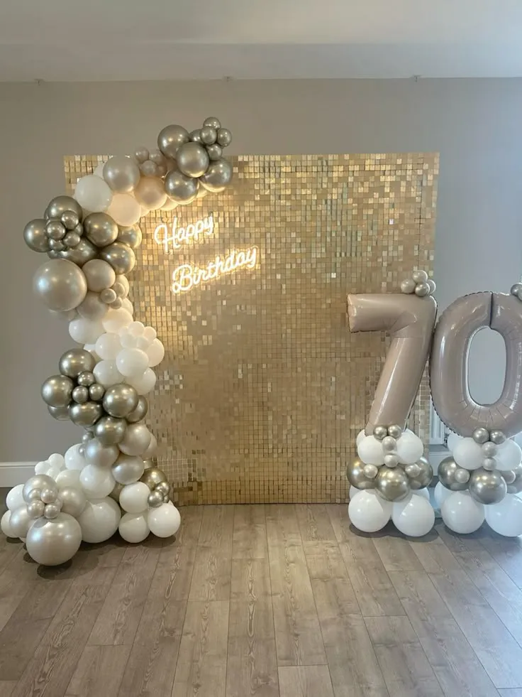 Silver shimmer half arch birthday balloon decoration with white, metallic silver, and white sand balloons, large 70 foil number balloon, and Happy Birthday wall sign in Dubai, UAE by Event Experts.