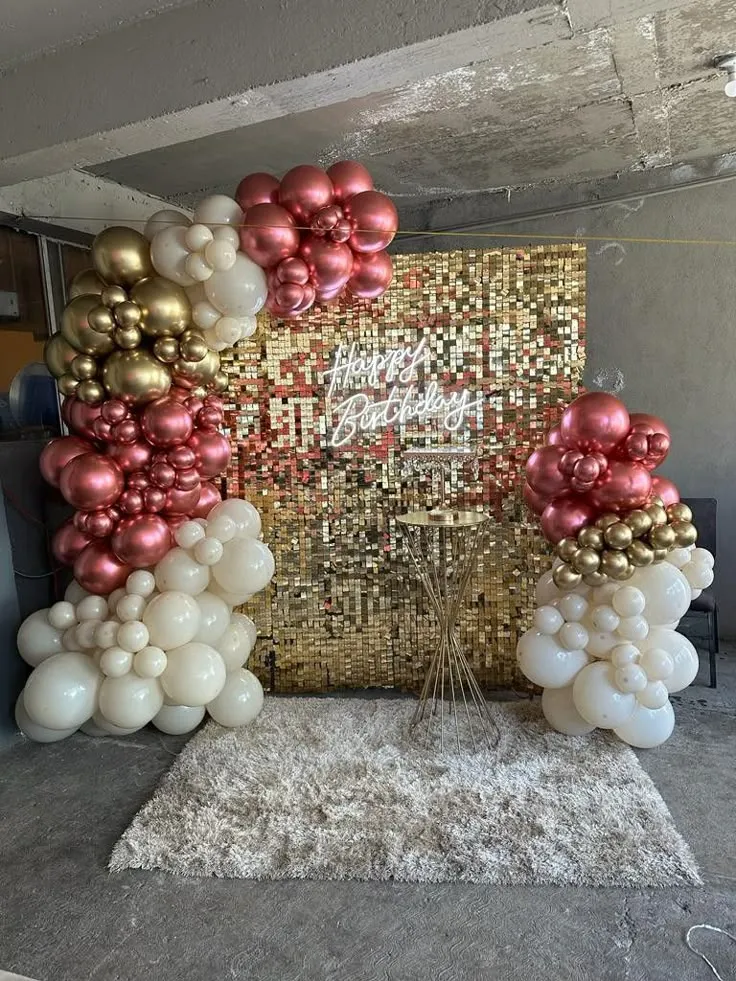 Golden shimmer half arch birthday balloon decoration with rose gold, cream, golden, and white balloons, square cake table, and Happy Birthday wall sign in Dubai, UAE by Event Experts.