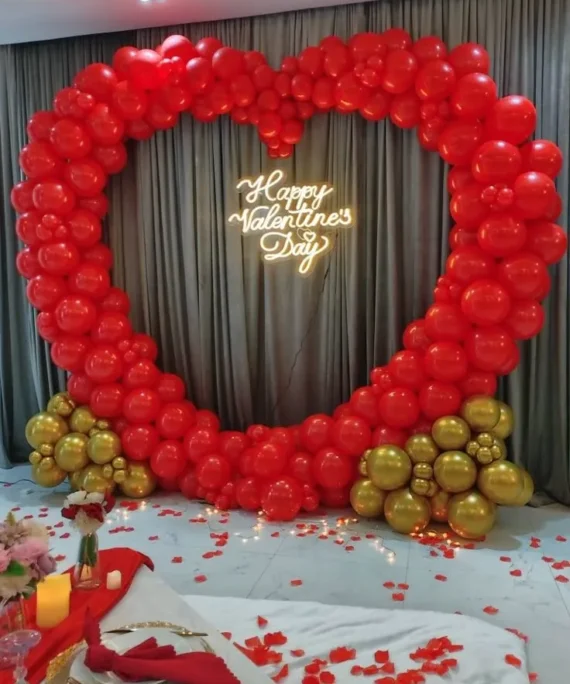 Valentine’s Day heart arch balloon decoration with red and golden balloons, rose petals, candles, in Dubai, UAE by Event Experts.