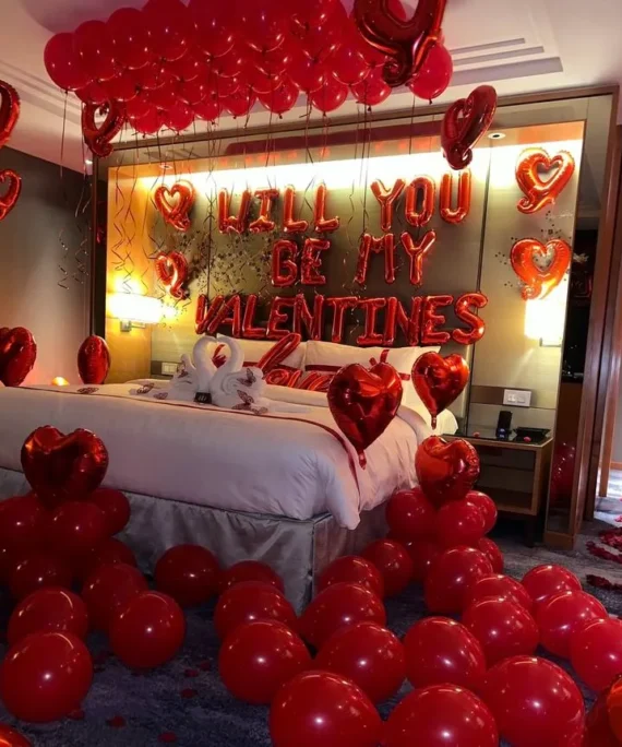 Valentine’s Day balloon decoration with 20 red helium balloons on the wall, 4 red foil heart balloons, 2 normal red foil hearts, 10 hanging red foil hearts, floor balloons, and Valentine & Love foil balloons in Dubai, UAE by Event Experts.