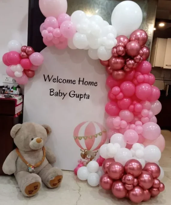 Welcome Baby balloon decoration with rose gold, white, light pink, and dark pink balloons, Welcome Baby board backdrop, and medium teddy in Dubai, UAE by Event Experts.