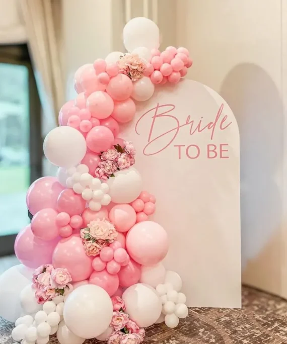 Bride welcome balloon arch setup with pink and white balloons, artificial roses, bride to be banner and white backdrop by Event Experts UAE
