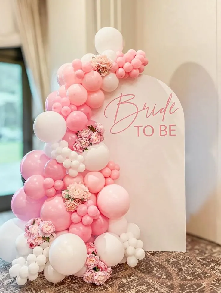 Bride welcome balloon arch setup with pink and white balloons, artificial roses, bride to be banner and white backdrop by Event Experts UAE
