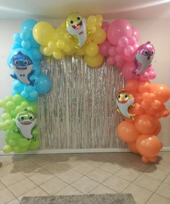 Baby shark theme balloon arch setup with blue yellow green pink orange balloons, 5 baby shark cutouts and silver backdrop banner by Event Experts UAE