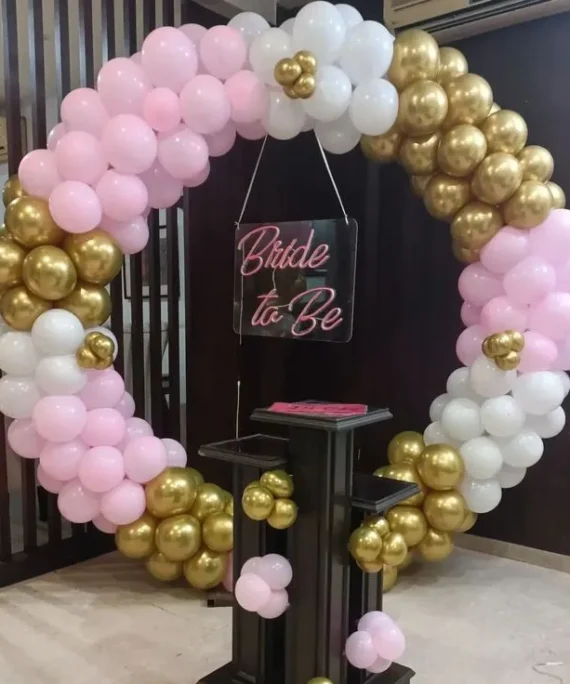 Bride round frame arch balloon setup with light pink, white and golden balloons, bride to be foil banner and white round cake table by Event Experts UAE