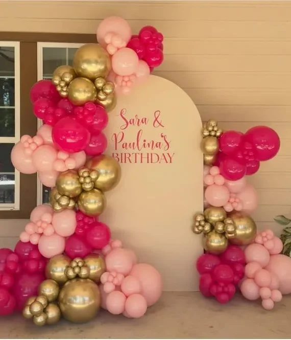 Half arch backdrop balloon decoration setup with light pink, dark pink, and gold balloons, oversized balloons, white round cake table, and Happy Birthday printed backdrop board.