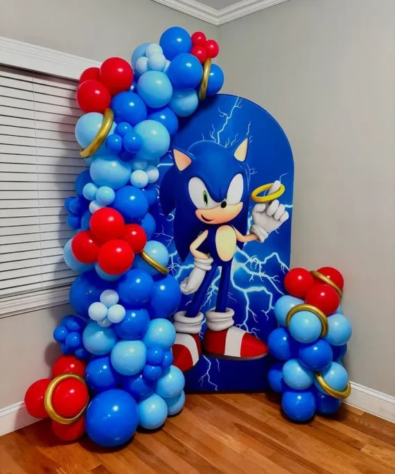 Sonic theme half arch backdrop balloon decoration setup with royal blue, light blue, red balloons, and gold ring foil balloons.