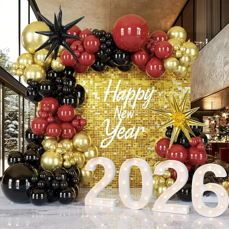 Happy New Year 2027 shimmer panel balloon decoration setup with red, black, and gold balloons, black and gold foil star balloons, Happy New Year foil banner, and golden square cake tables.