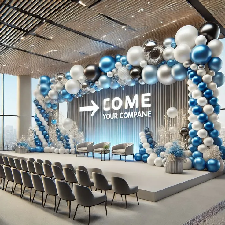 Corporate event big balloon arch decoration setup with light blue, white, dark blue, silver, and black balloons, artificial white flowers, large balloons, floor balloon bunches, wall balloons, and white round cake tables.