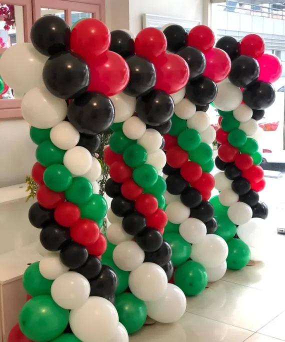 Set of four UAE National Day balloon pillars with white, red, black, and green balloons topped with balloon flower decorations.