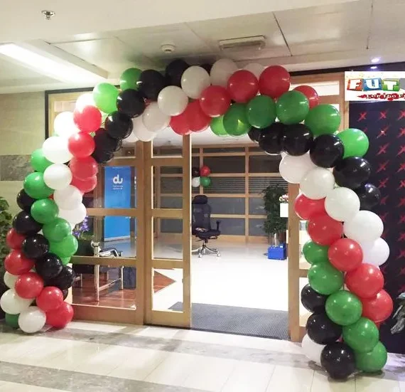 UAE National Day balloon arch decoration setup with black, white, red, and green balloons and matching balloon bunches on the wall.