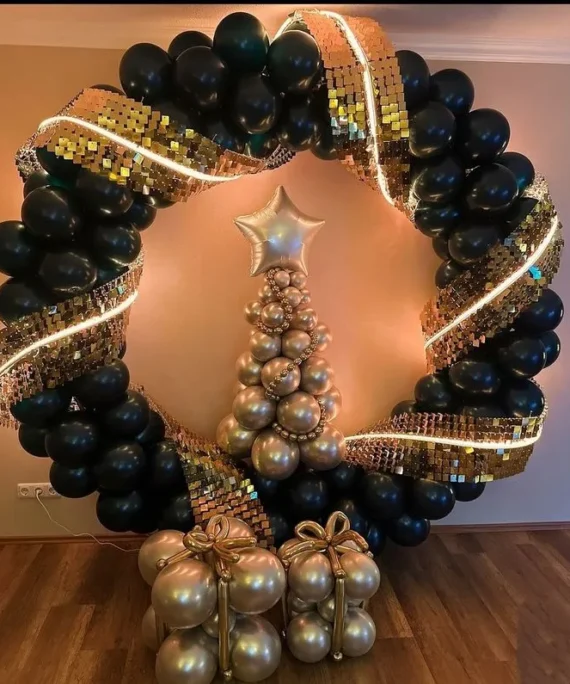Happy New Year and Christmas round frame shimmer balloon decoration setup with black balloons, rose gold Christmas tree balloon, foil star balloon, white round cake table, LED frame light, and floor balloon bunches.