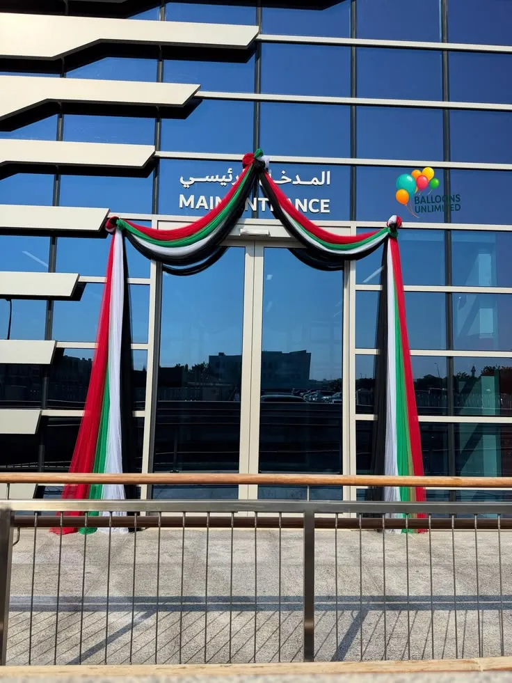 UAE National Day office reception balloon net decoration setup with red, black, green, and white balloon net, UAE foil balloons, UAE flags, and hanging balloon net décor.